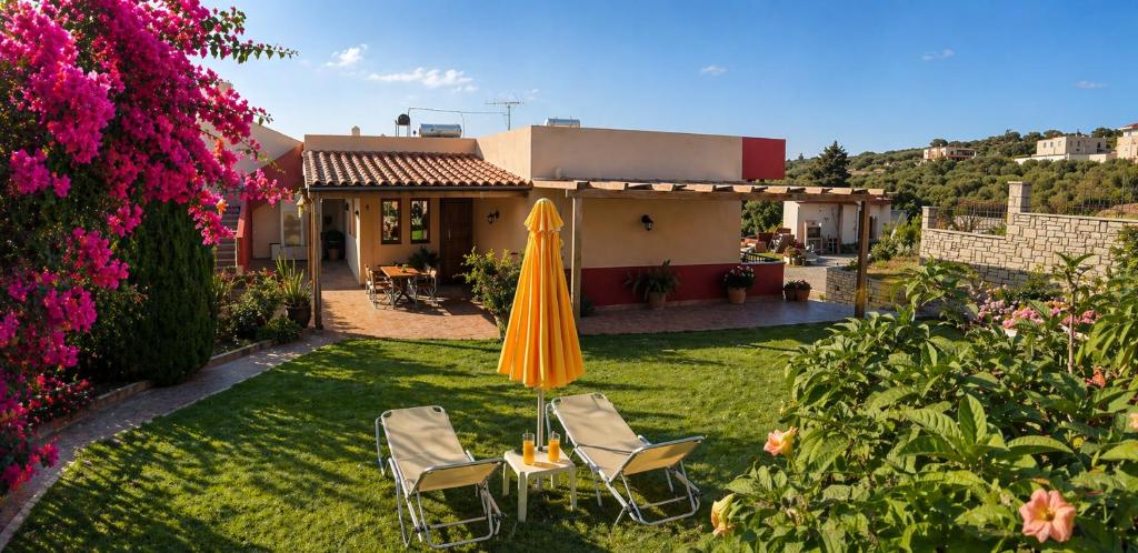 a patio with an umbrella and chairs in a yard at Argyroupolis Dimitris Rooms in Argyroupolis