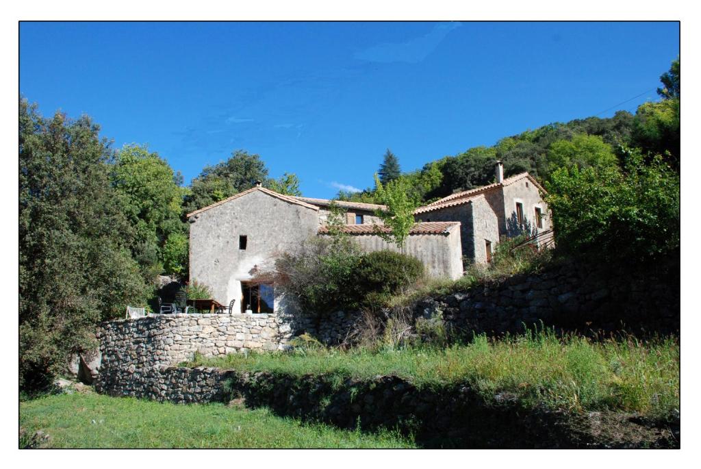 ein Haus auf einem Hügel mit einer Steinmauer in der Unterkunft Mas des Nabières in Saint-Martial