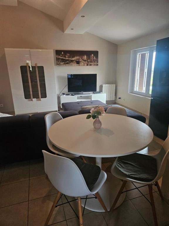 a dining room with a white table and chairs at Appartement T2 in Vaugneray