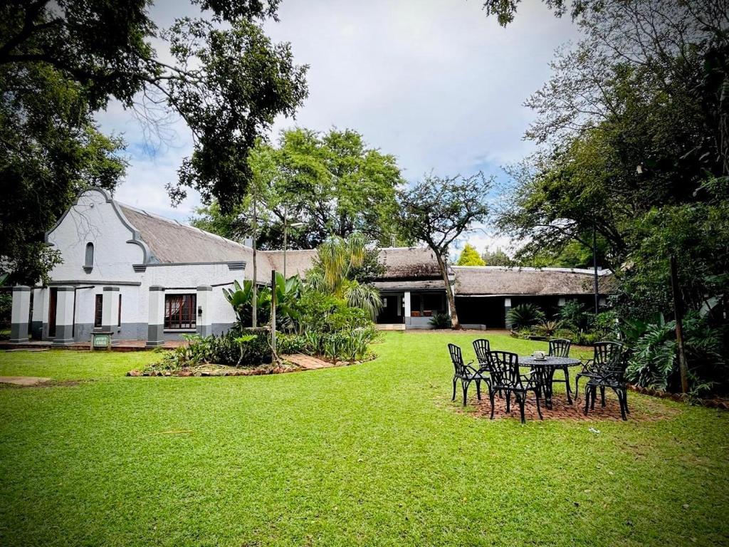 a yard with chairs and a table in front of a house at Phumulani Lodge Kameeldrift in Pretoria