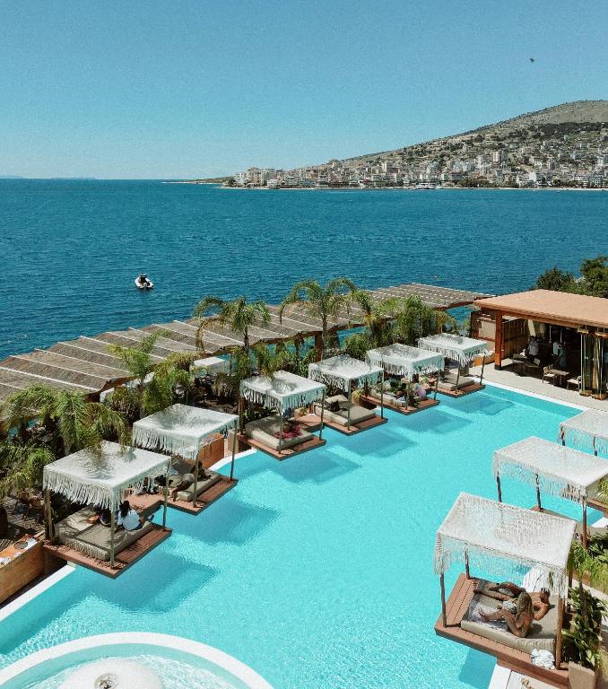 a resort with a large swimming pool next to the ocean at Lost Seaside Hotel - Adults Only in Sarandë