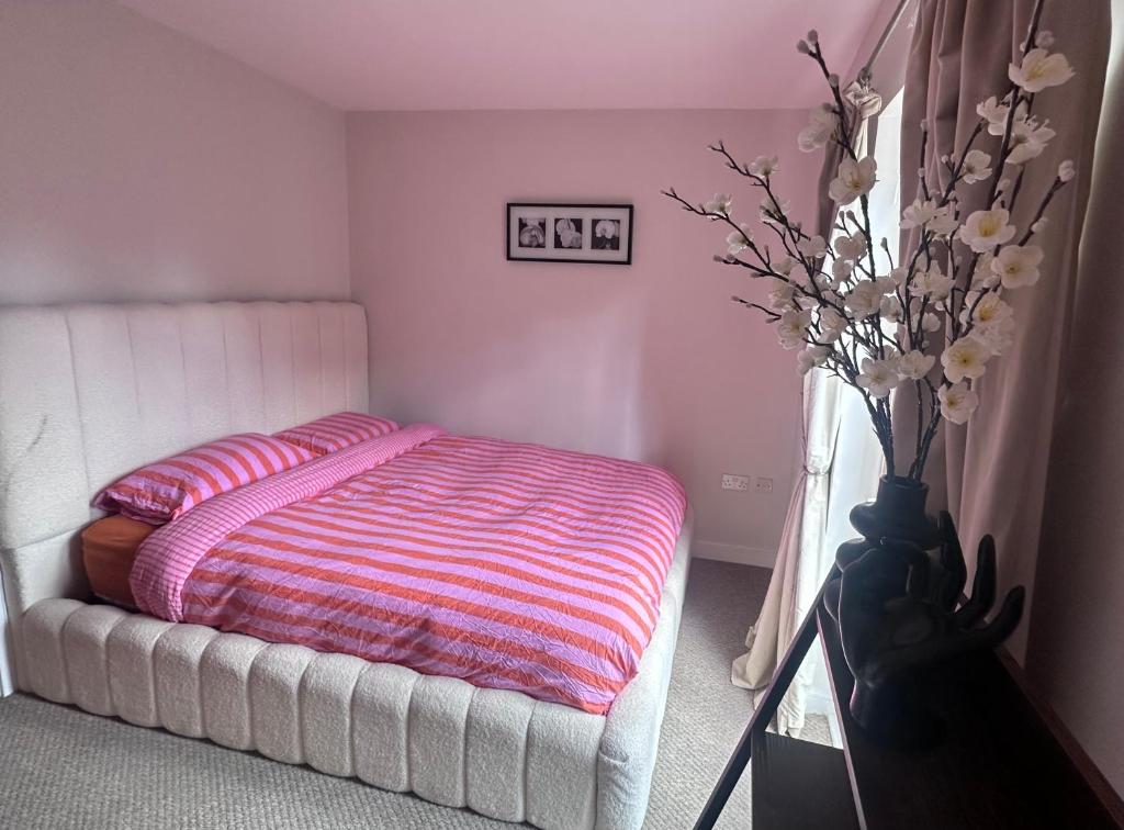 a bedroom with a bed and a vase with flowers at Modern 2 bed flat with parking by Bluewater shopping mall in Greenhithe