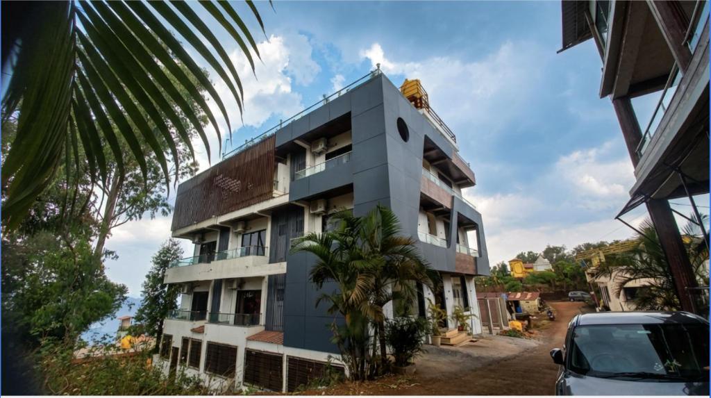a building with a palm tree in front of it at Omkar Hotel - Mahabaleshwar in Panchgani