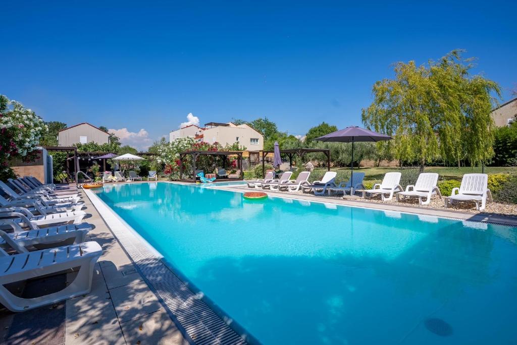 a large swimming pool with chairs and umbrellas at My Nest Accommodation in Privlaka