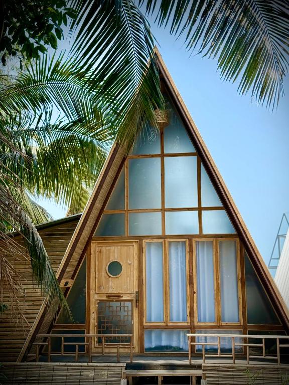 a house with a large window and a palm tree at Chader Bari Beach Resort, Cox's Bazar in Cox's Bazar
