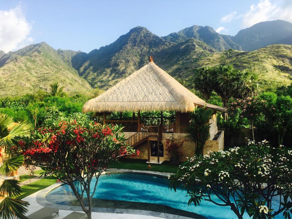 a resort with a pool and mountains in the background at Sun Suko Boutique Resort & Yoga Retreat in Pemuteran