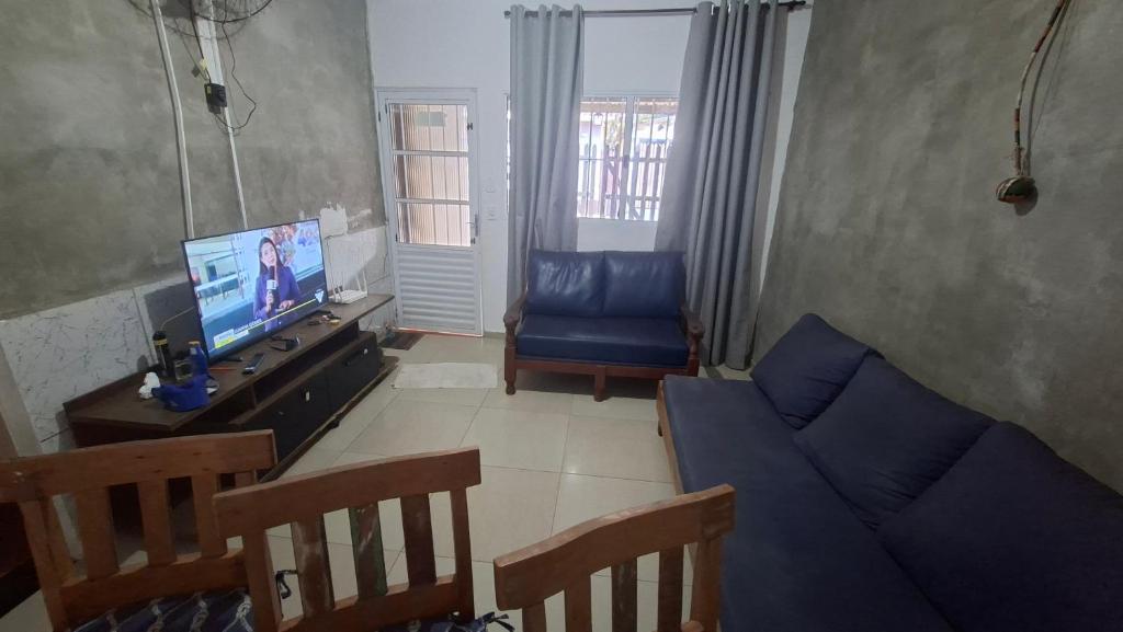 a living room with a blue couch and a television at Casa 2 minutos a pé da Praia de INDAIÁ in Bertioga