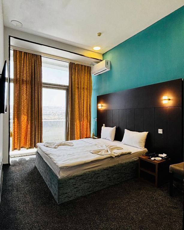 a bedroom with a large bed with a large window at Crossway Hotel Baku in Baku