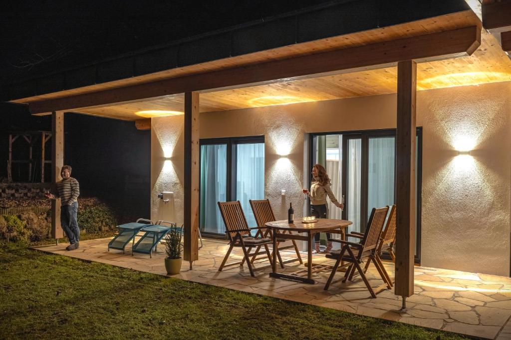 a man and a woman standing on a patio at night at Alpen Studio ZweiZeit in Tröpolach