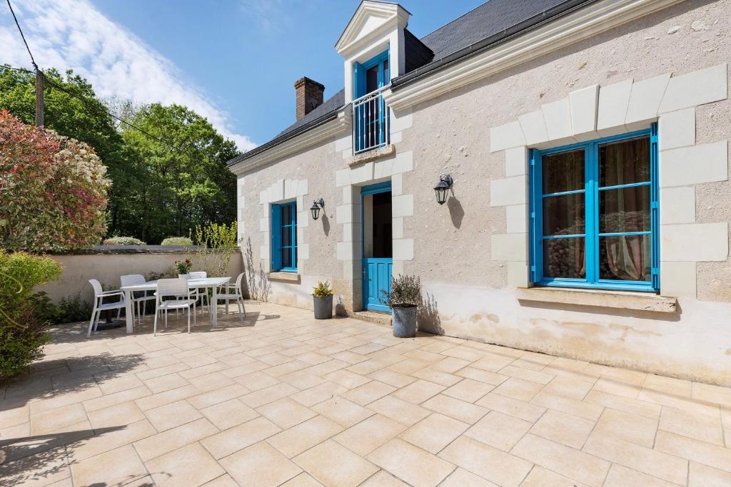 a patio with tables and chairs in front of a house at Gîte La Clématite in Mosnes