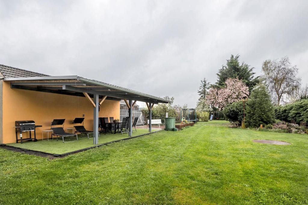 a patio with chairs and tables on a lawn at Familienhaus mit riesigem Garten in Arnsdorf