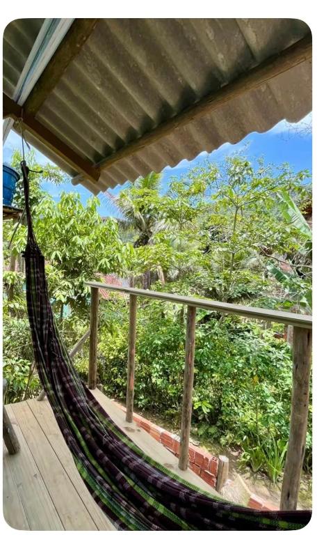 a hammock on a deck with a view of trees at Chalé da jessica in Paraty