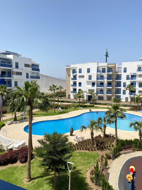 a view of a swimming pool with palm trees and buildings at Luxury Apartment in martil in Martil