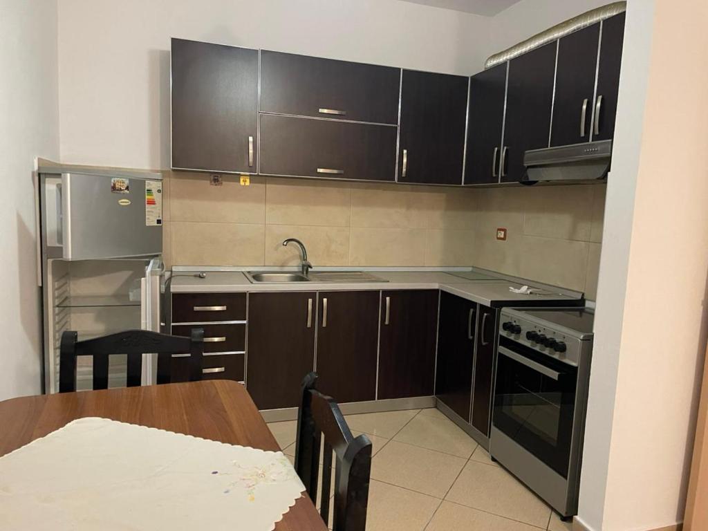 a kitchen with brown cabinets and a sink and a table at Endi Apartments 2 in Tirana