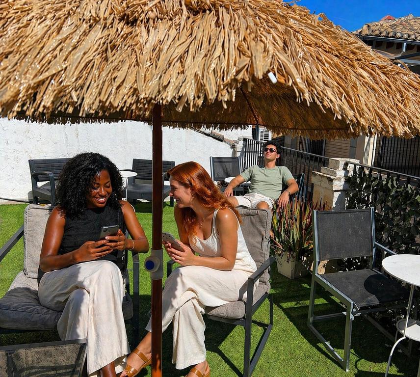 two women sitting in chairs under a straw umbrella at Oh! My Hostel in Granada