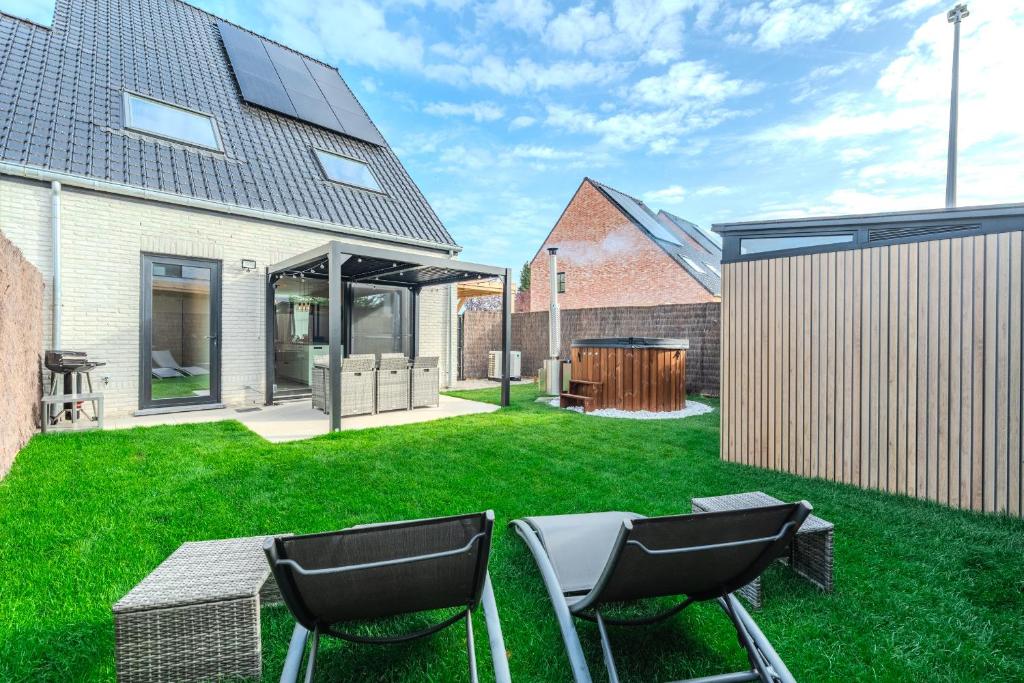 a backyard with two chairs on the grass at vakantiewoning T'is ier goed in Jabbeke