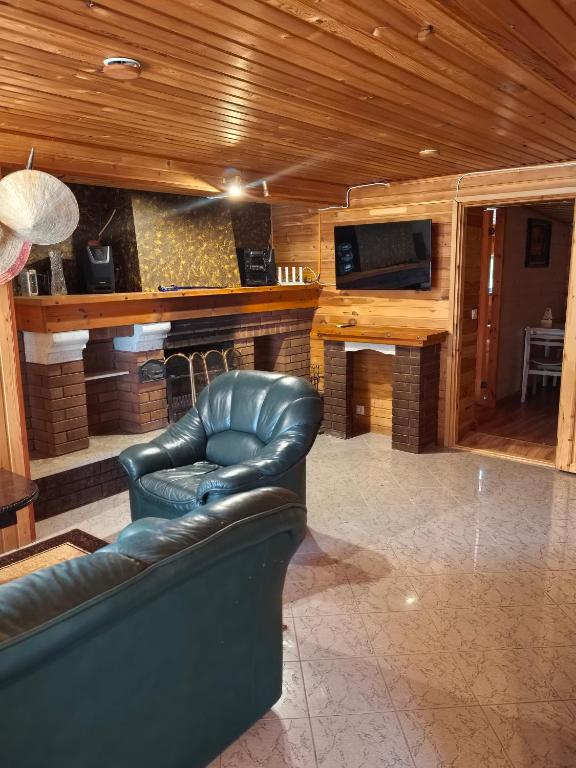 a living room with a leather couch and a fireplace at Дом у моря in Suurupi