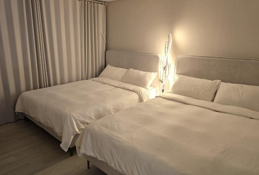 two beds sitting next to each other in a bedroom at 심, 쉼 Stay Hwangridan-gil 침대4개 8인숙소 in Gyeongju