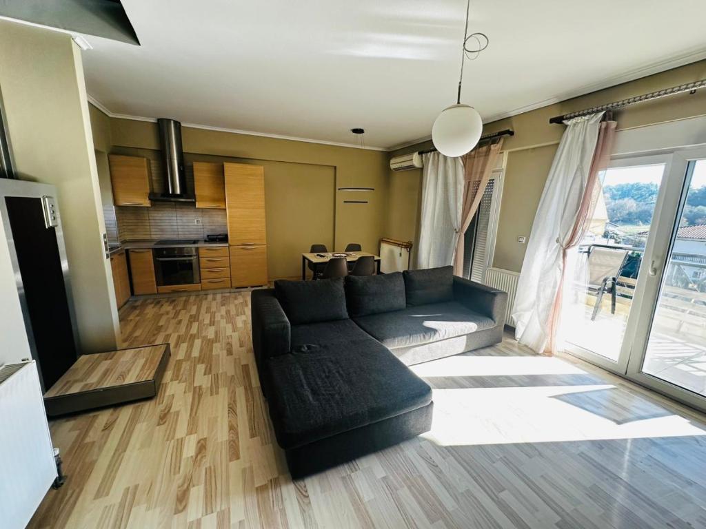 a living room with a black couch and a kitchen at JD Maisonette for 4 in Neoi Epivates