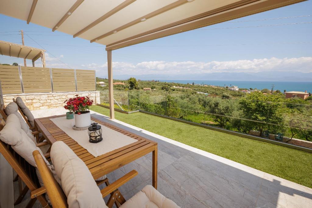 a patio with a table and chairs and a view of the ocean at Petra & Thea Chrani Villas in Chrani