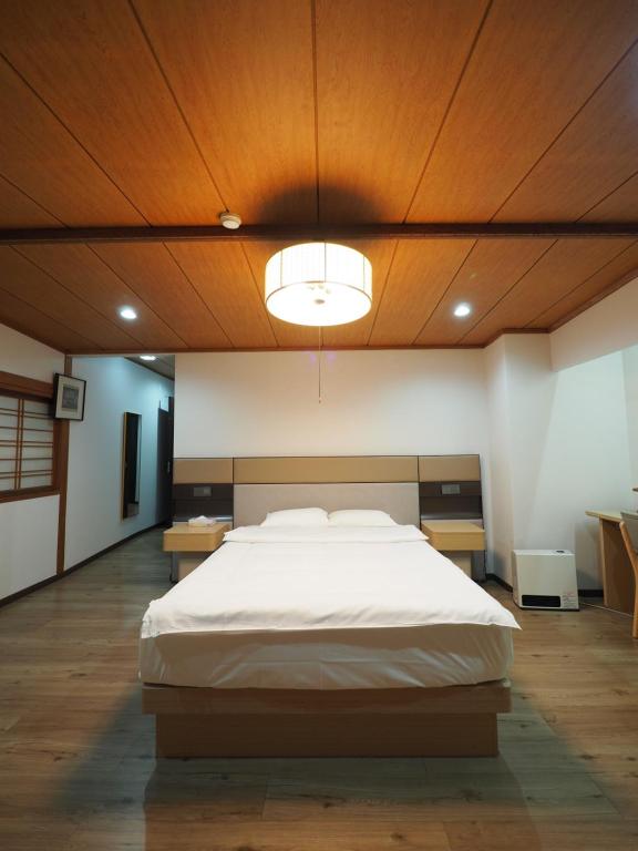 a bedroom with a large bed with a wooden ceiling at Kurmon Inn in Omachi