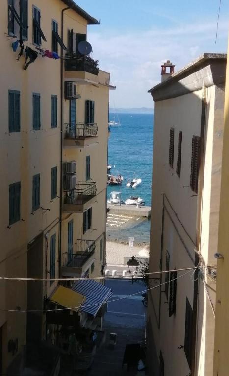 a view of the ocean from between two buildings at Casa Per 2 in Porto Santo Stefano