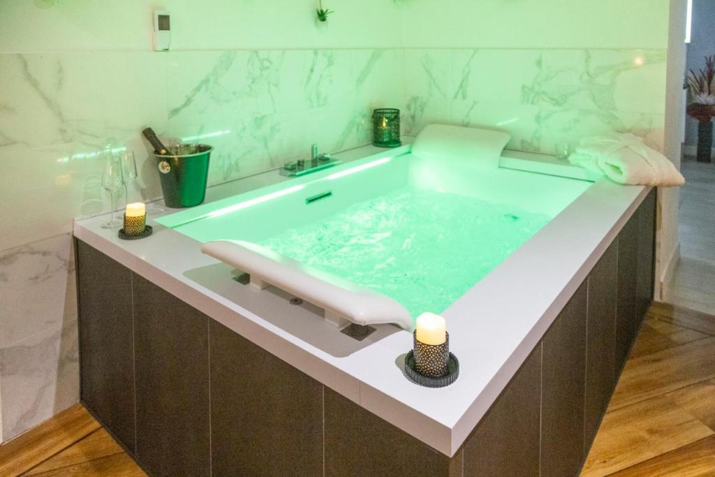 a bathroom with a tub with two candles in it at Le Carpe Diem - Détente & Bien-être - Balnéo, Sauna, CLIM, Terrasse, Parking privé in Dole