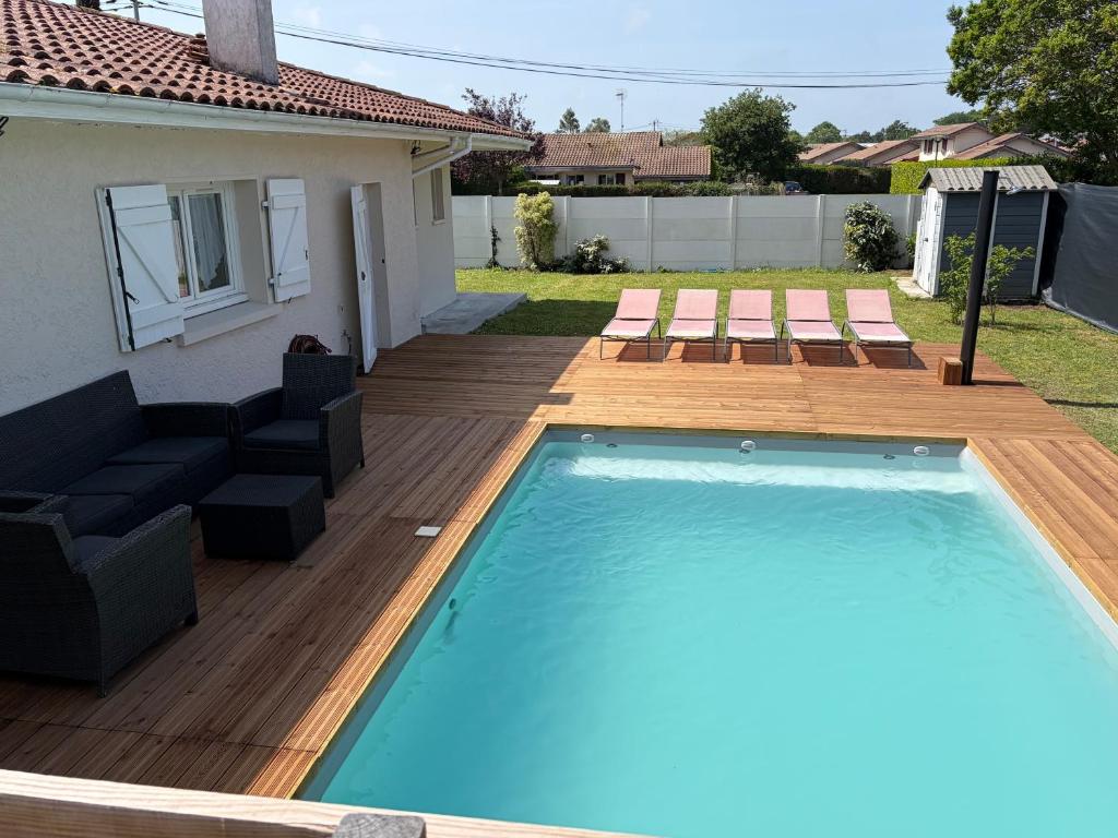 a swimming pool with a deck and a house at Studio cosy avec piscine à 10 min Hossegor in Saint-Vincent-de-Tyrosse