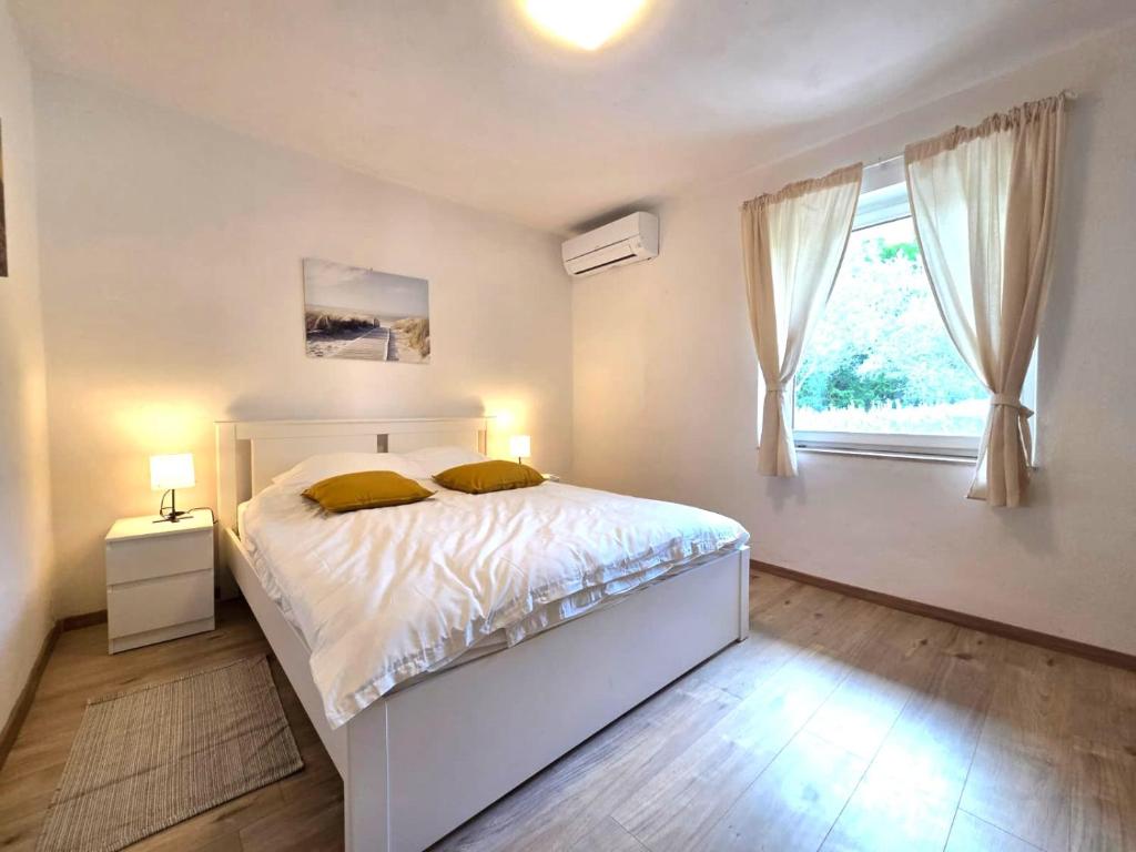 a white bedroom with a bed and a window at Apartman Filip in Risika