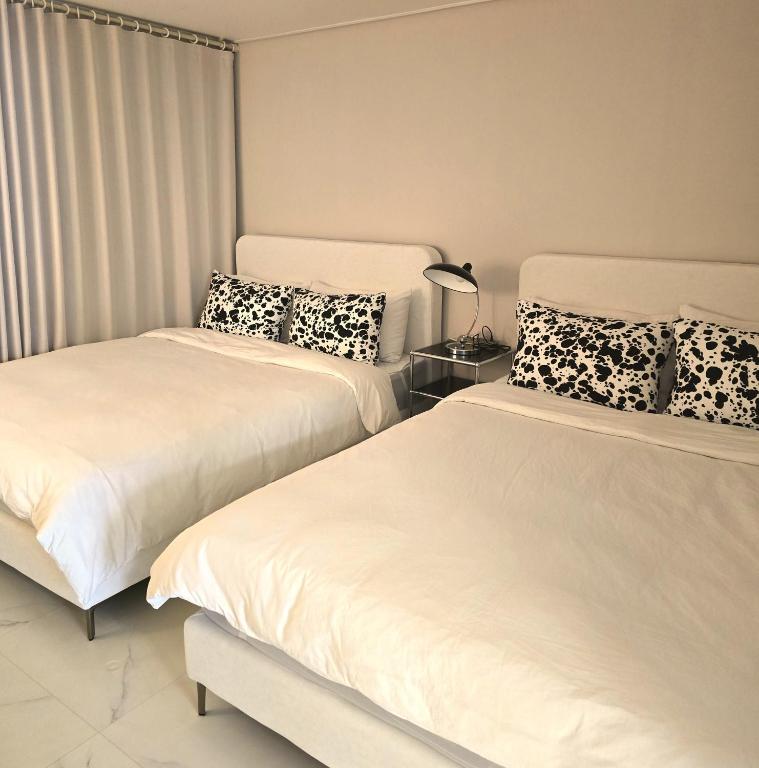 two beds sitting next to each other in a bedroom at Stay Chic 황리단길 룸3 침대5 에어컨4 에어랩 건식사우나 동궁과월지 in Gyeongju