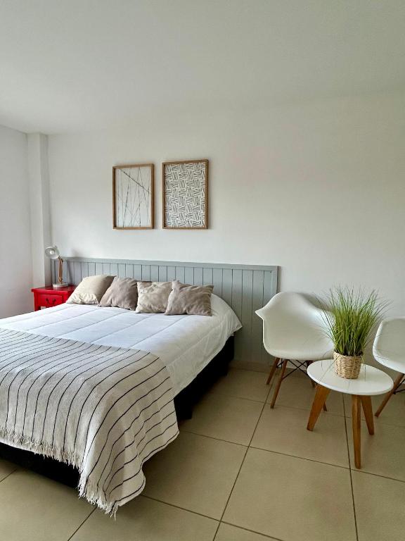 a bedroom with a large bed and a white chair at Penguins Flats 3 in Ushuaia