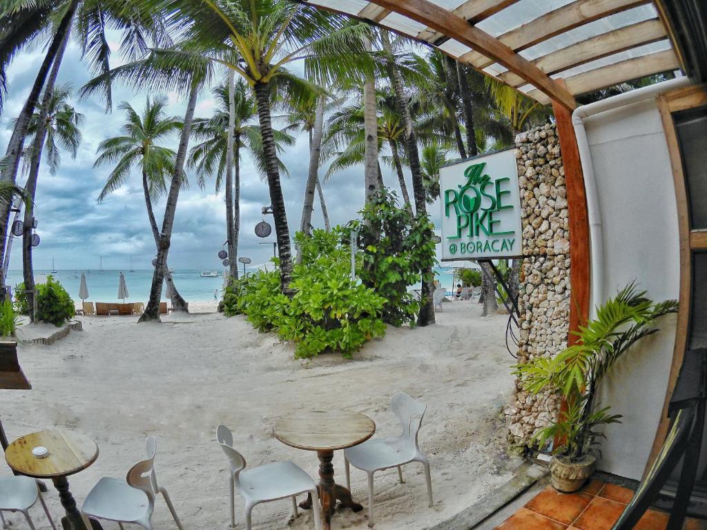 a cafe on the beach with palm trees and a table and chairs at The Rose Pike at Boracay in Boracay
