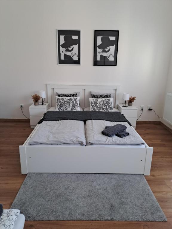 a white bed in a white bedroom with two tables at Apartman MWM Brno 2 in Brno