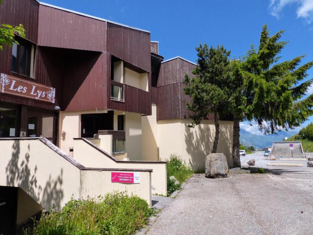 a building with a tree in front of it at travelski home select - Résidence Les Lys in Les Menuires