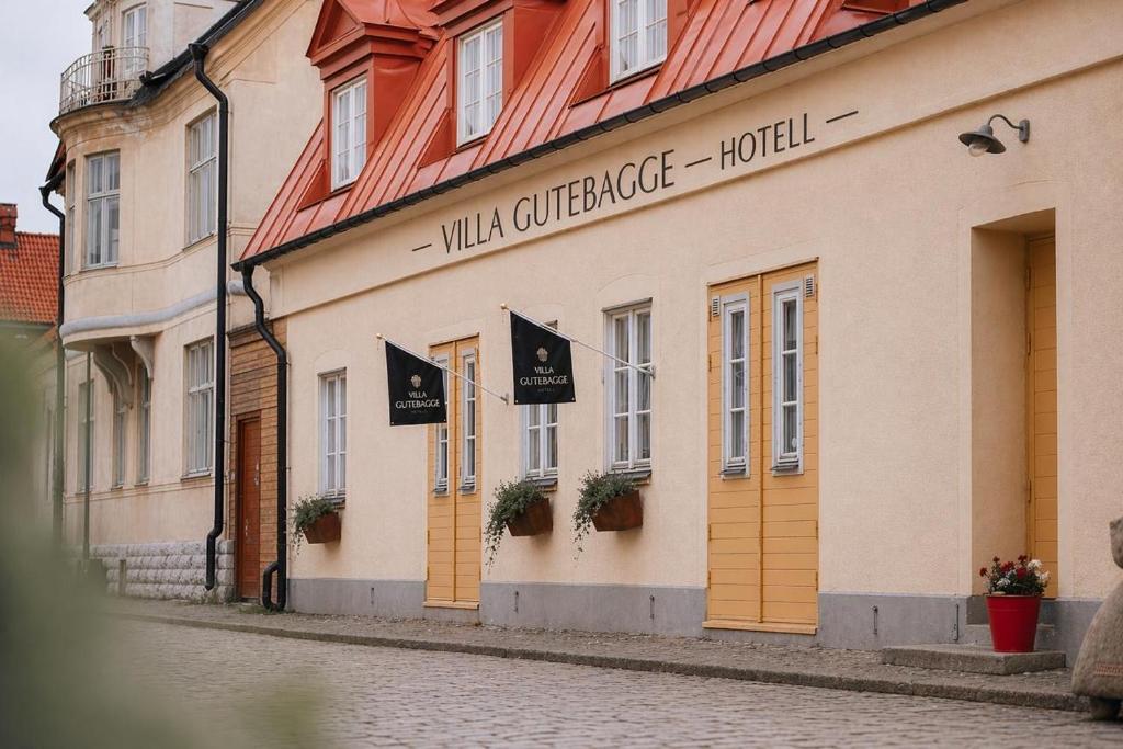 a building on a street with flags on it at Villa Gutebagge Hotell in Visby