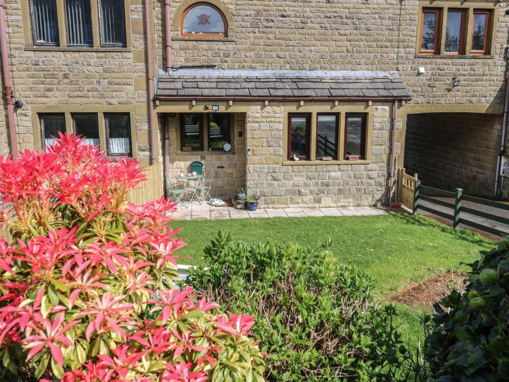 a brick house with a yard with pink flowers at Underview in Holmfirth