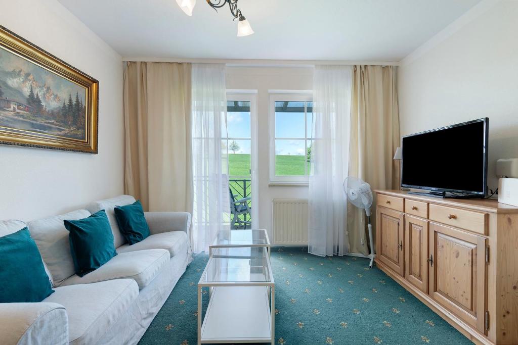 a living room with a couch and a tv at Apartment mit Gartenblick K1 206 in Spalt