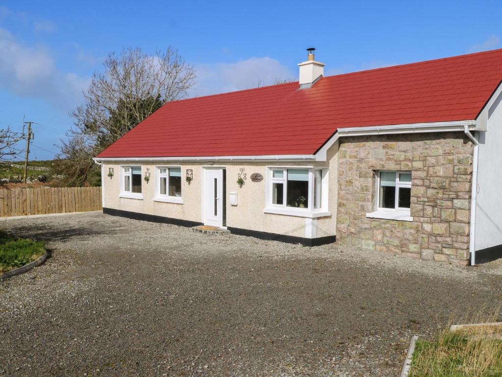 a house with a red roof on a gravel driveway at Red House in Galway