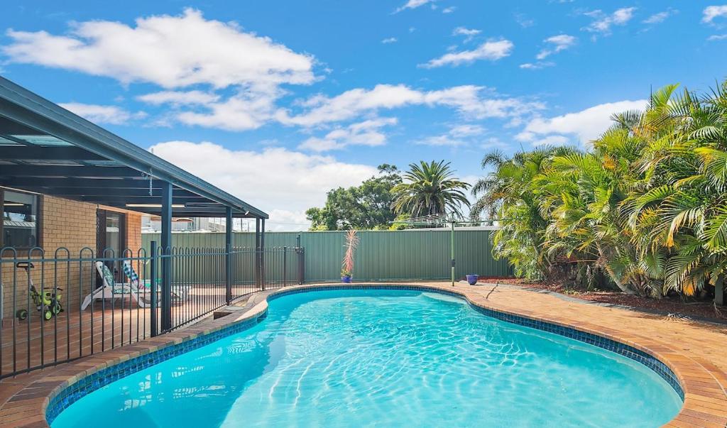 a swimming pool in a yard with a fence and trees at Spacious home with pool in Kippa-Ring in Newport