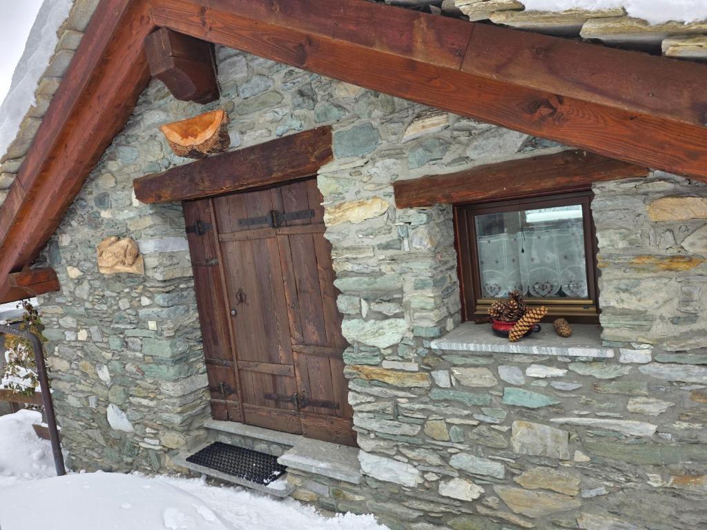 a stone building with a wooden door and a window at la casa del marmottaio in Crépin