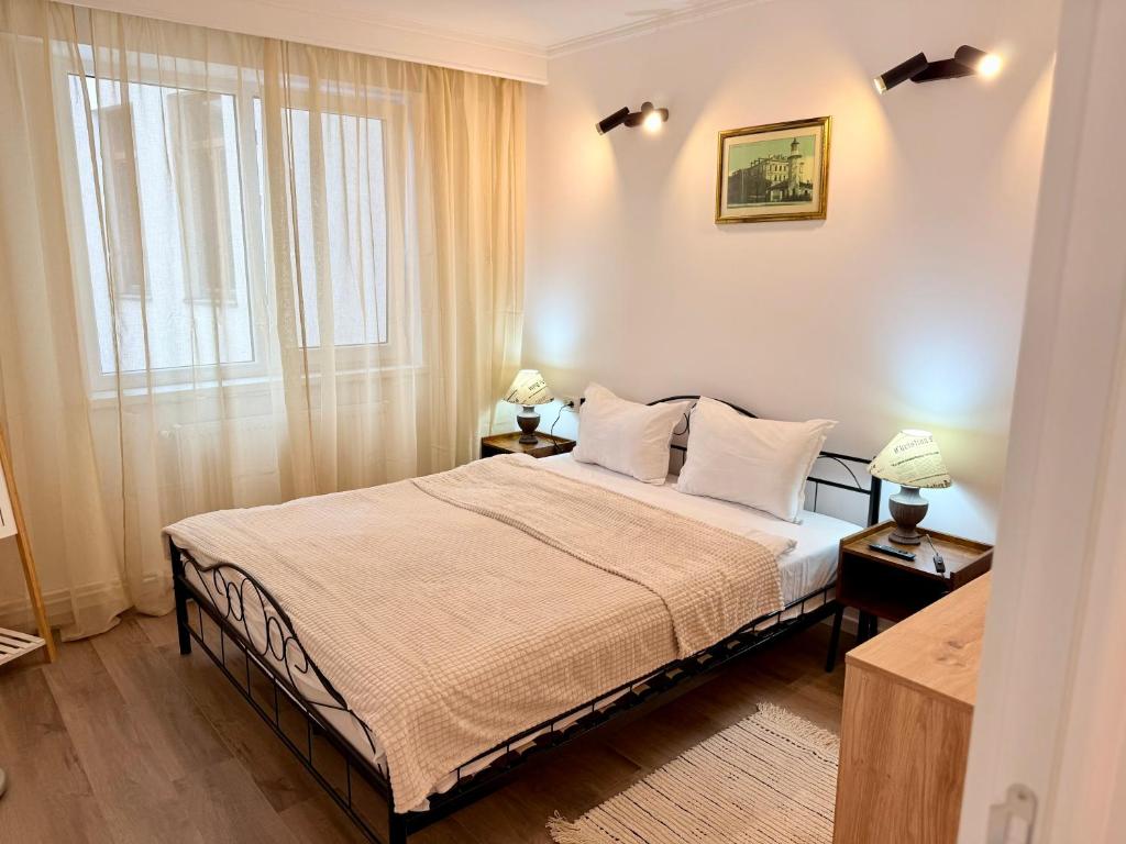 a bedroom with a bed with white sheets and a window at Piața Ovidiu 14 Loft in Constanţa