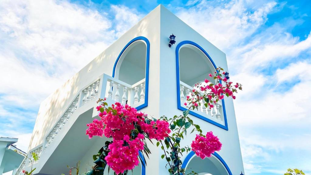 a white church with pink flowers in front of it at De BOUGENVILLE Tulap Beach Front in Watulanei