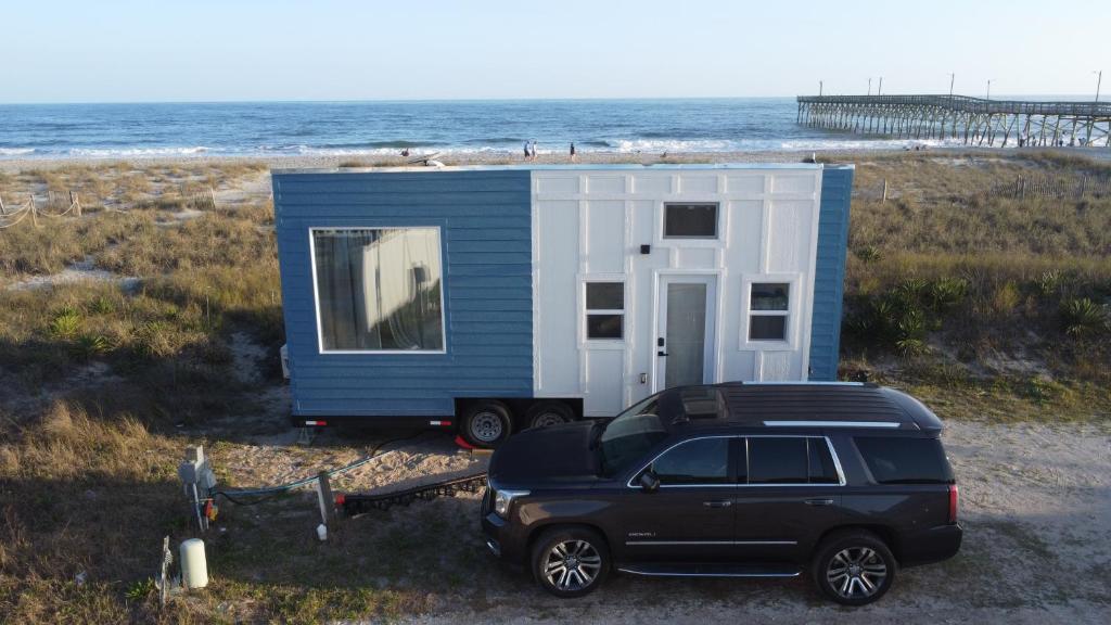 a car parked in front of a tiny house on the beach at Oceanfront Tiny Retreat in Holden Beach