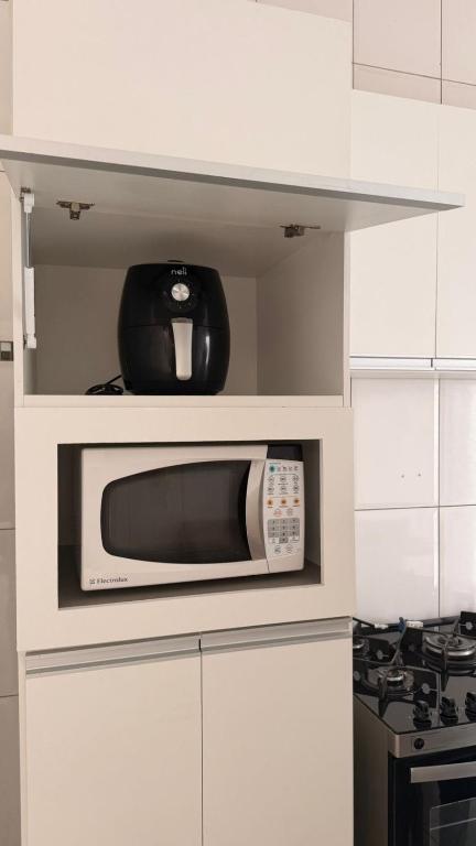 a microwave sitting on top of a white kitchen cabinets at Casa jatobá in Petrolina
