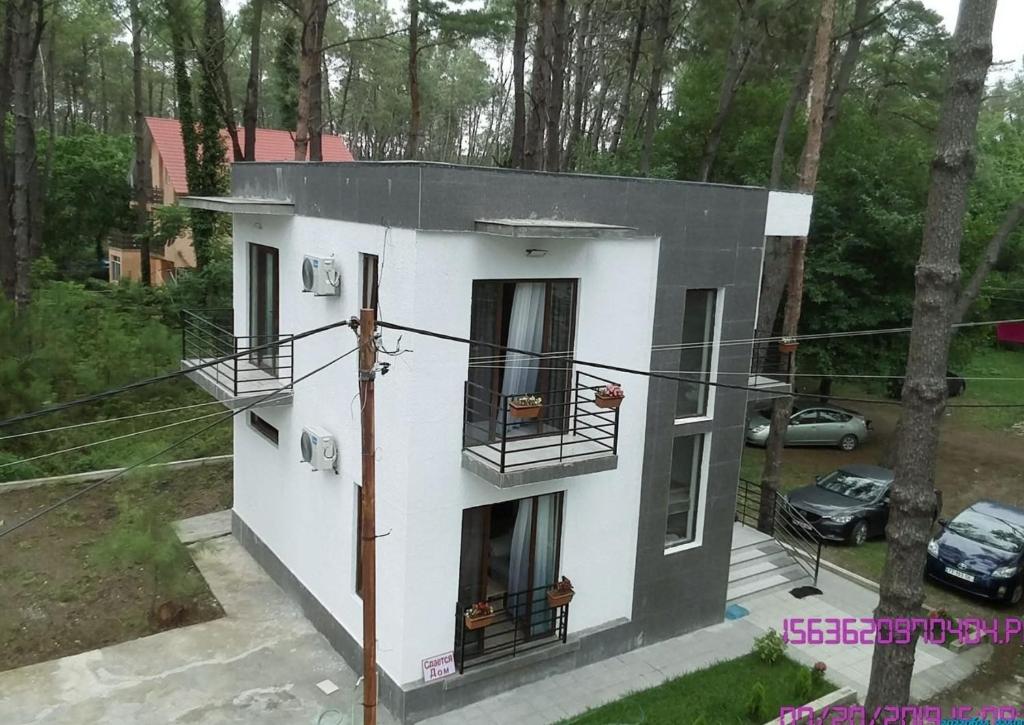 a white house with two balconies and a car at SHEKVETILI s in Kokotauri