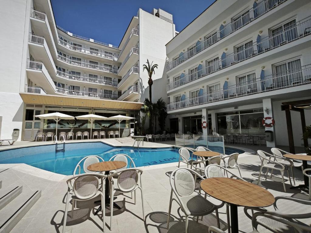 a hotel patio with tables and chairs next to a pool at Hotel Miami Calella in Calella