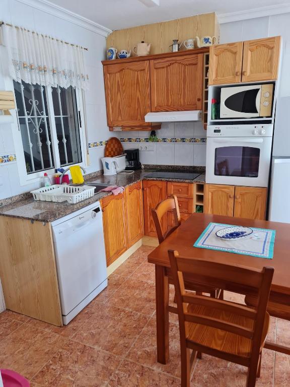a kitchen with white appliances and a wooden table at Casa Ingrid in San Fulgencio