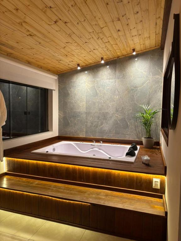 a large bath tub in a room with a window at Chalé Aconchego da Paz - Chalé 1 in Lavras Novas