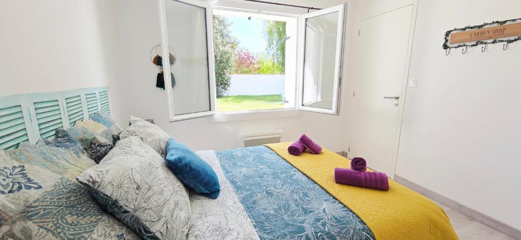 a bedroom with a bed with pillows and a window at Fleur De Cerisier Vendée in Challans
