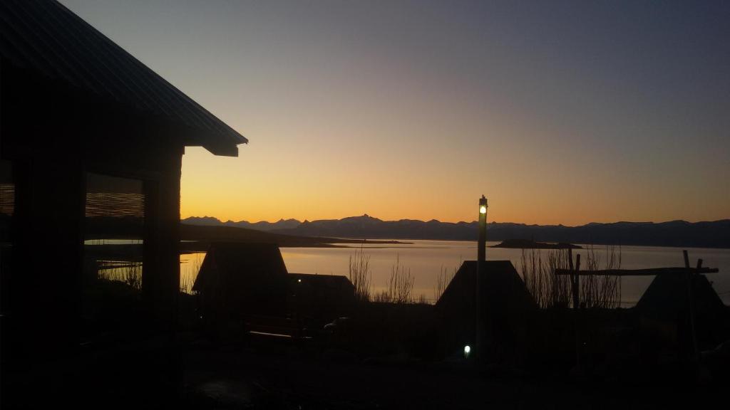 a sunset over a lake with a house and a street light at Brillos Patagónicos in El Calafate